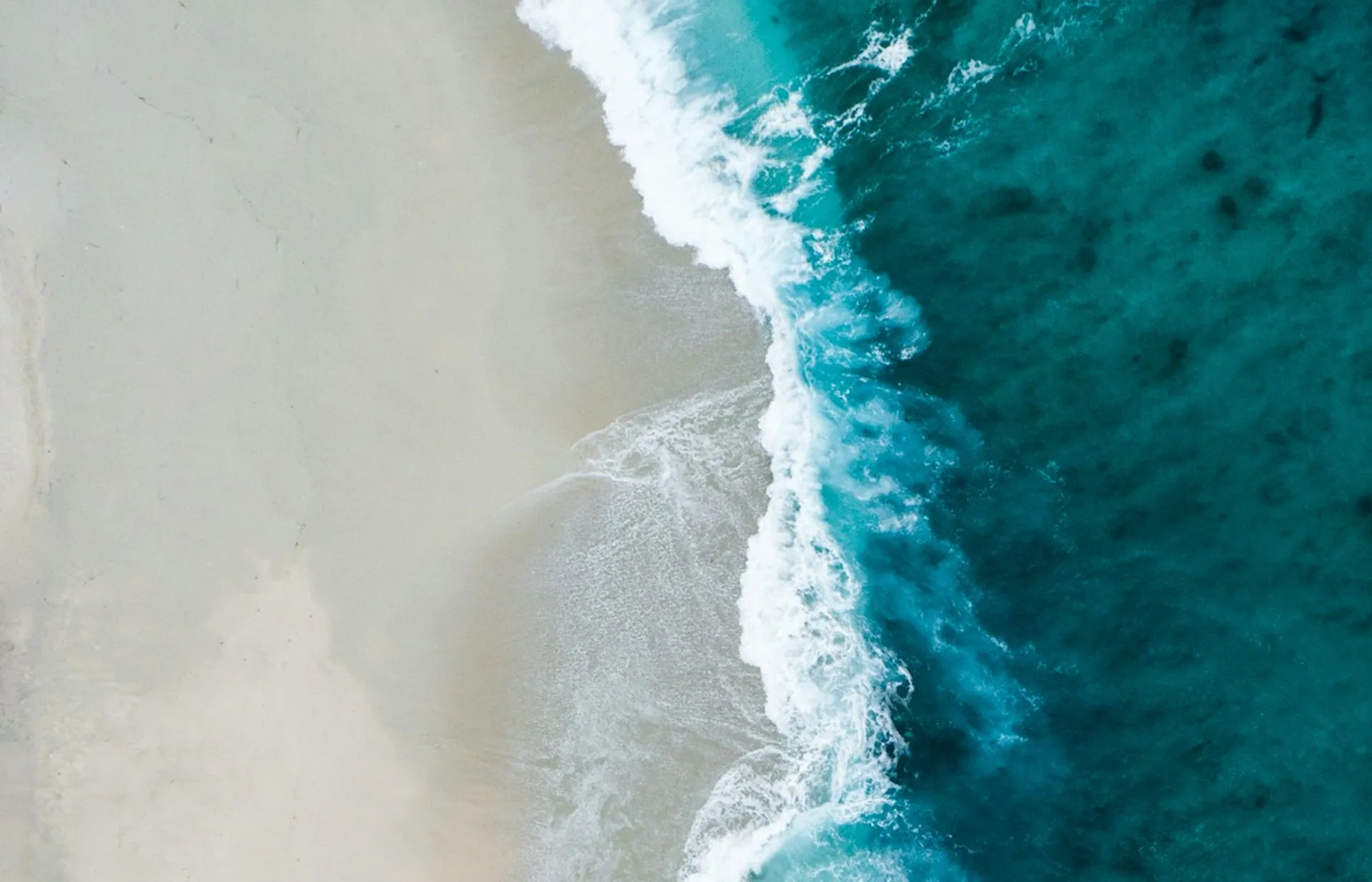 Aerial view of turquoise ocean wave Aerial view of turquoise ocean wave meeting a sandy beach