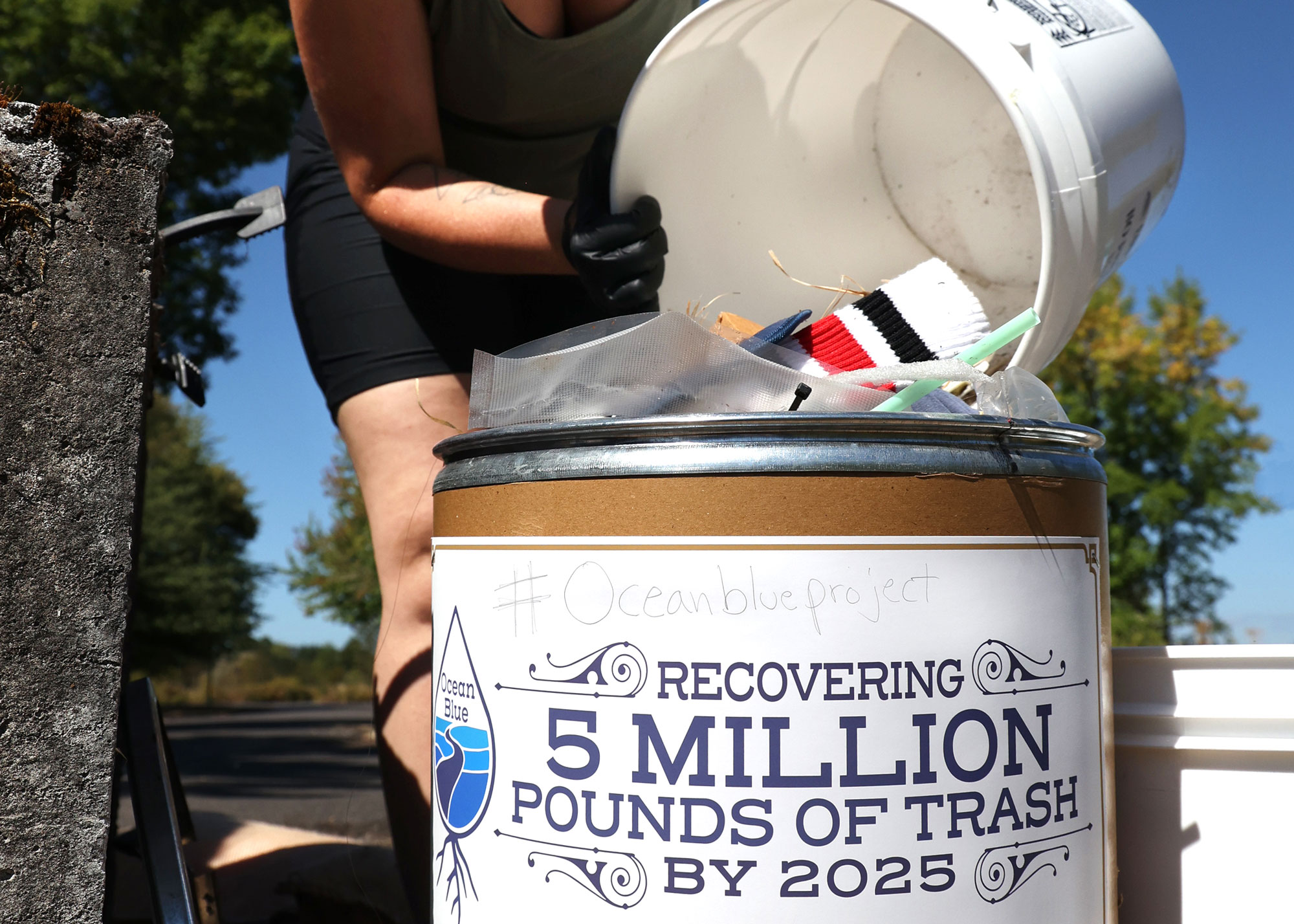 OceanBlueCleanUp_MountainRose_August2025 • Environmental Nonprofit Organization Volunteer emptying a bucket of debris into a receptacle.